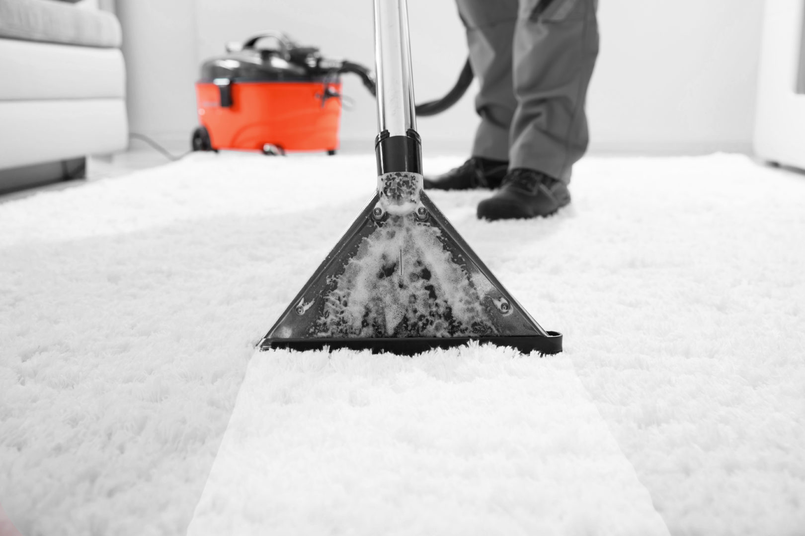 A Poppies of Hounslow male cleaner using a carpet cleaner on a living room thick rug