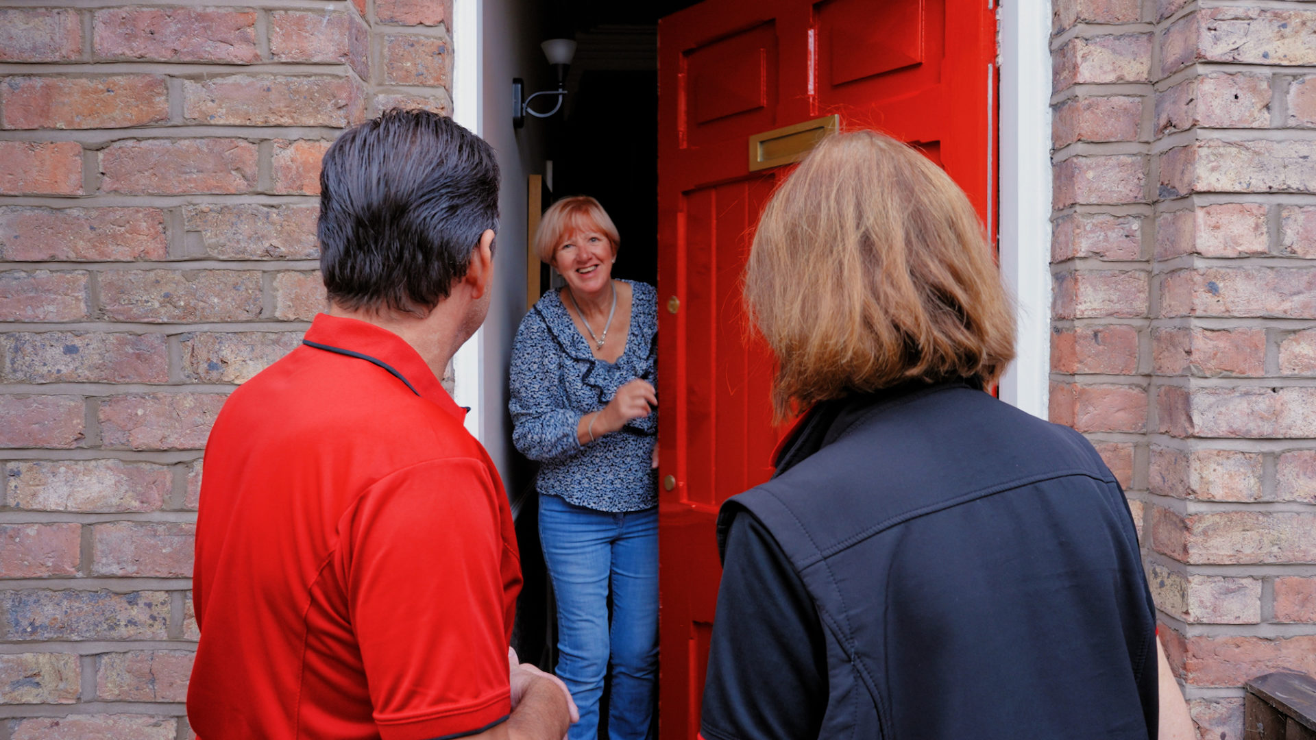 A woman opening the door to Poppies of Hounslow team members during a consultation visit