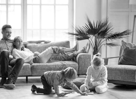 A picture of two parents watching their kid playing on a nice clean floor